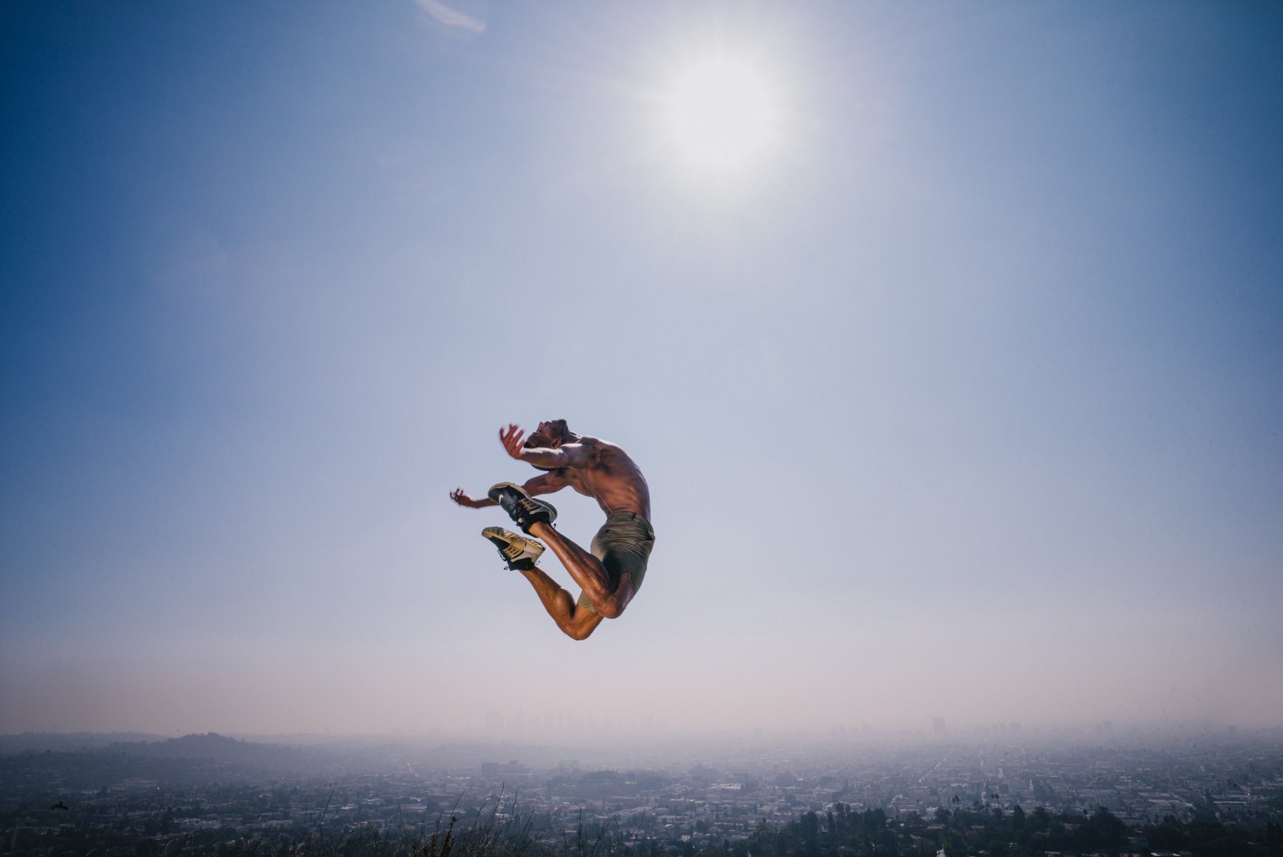 A dancer suspended in midair beneath the sun