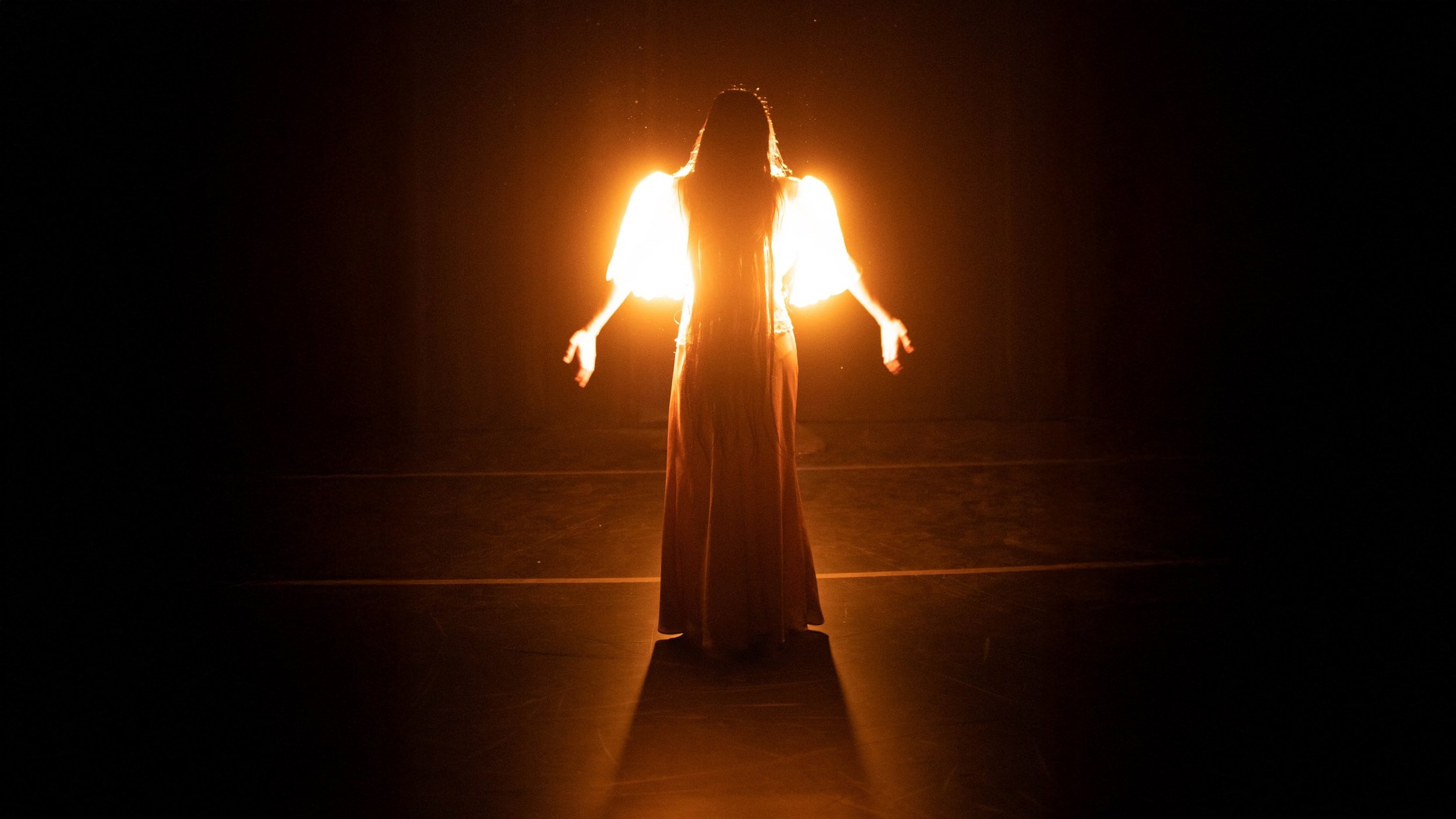 A performer illuminated by a glowing light on a dark stage