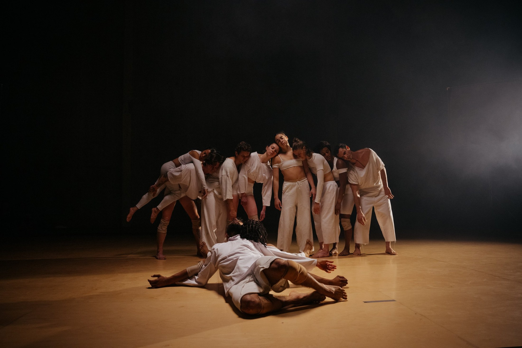 Dancers gathered on a warmly lit warehouse floor