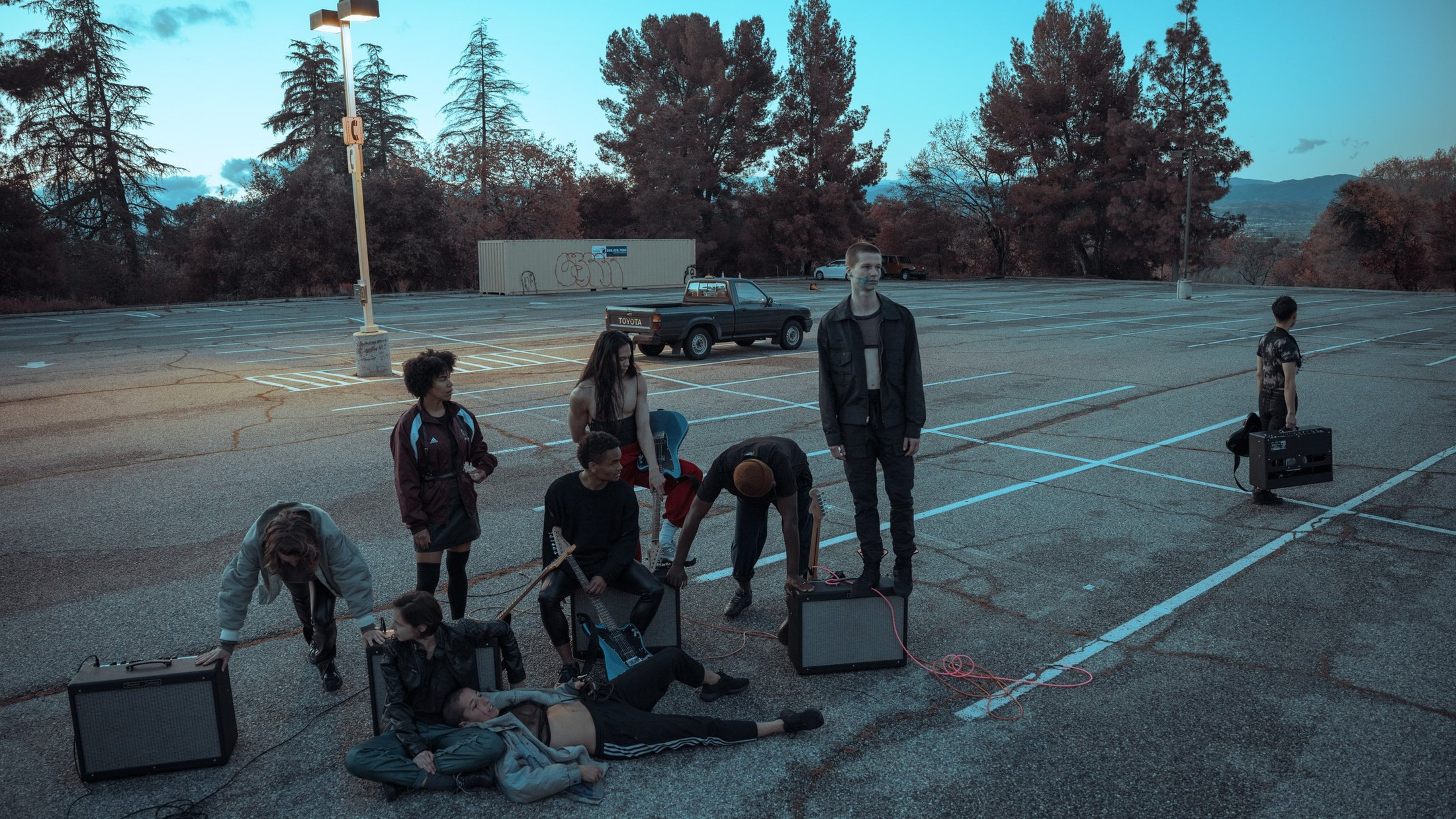 Dancers gathered with amplifiers outdoors at dusk